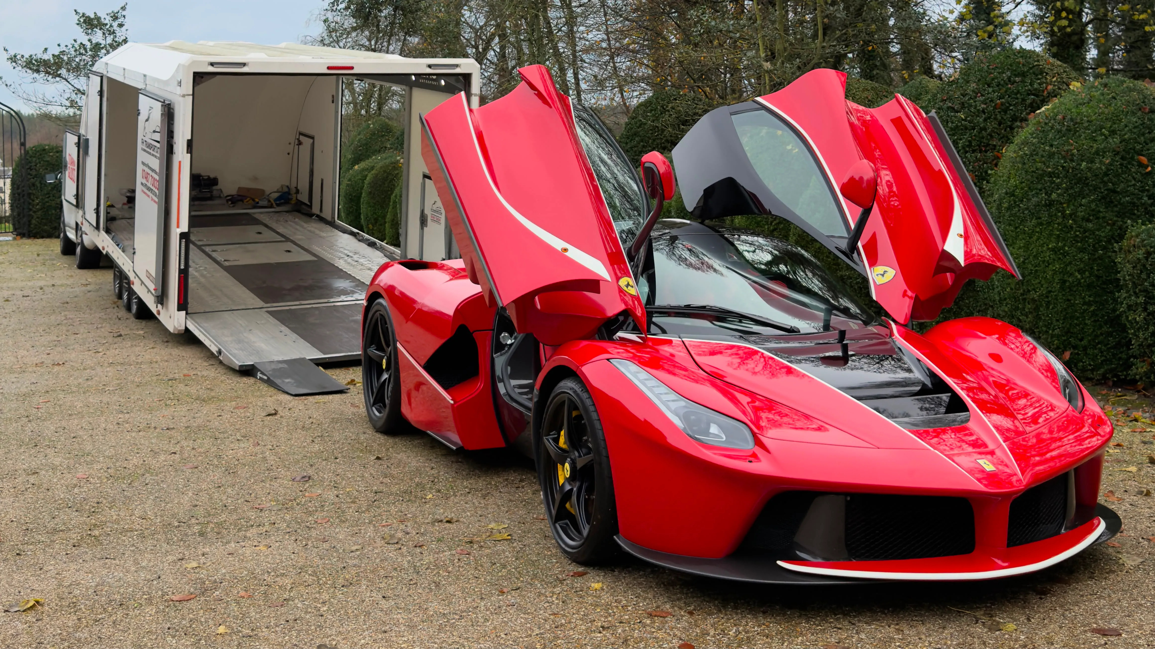 A LaFerrari with its doors open beside an open FH Transportation transporter